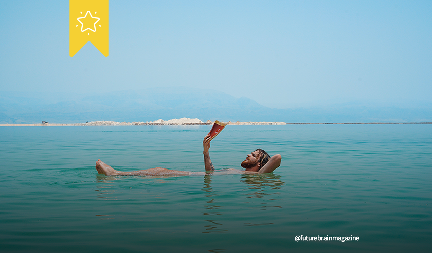 Uomo che legge in acqua al mare